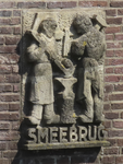 901688 Afbeelding van het dubbele zandstenen reliëf 'Het ambacht van de smid' (twee smeden met aambeeld) in 1948 ...